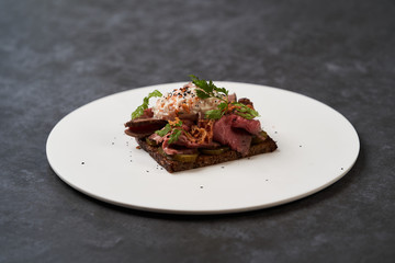 Smorrebrod with roast beef and remoulade sauce on a white plate