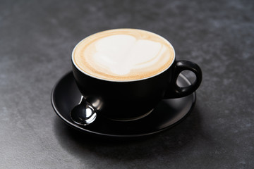 Cup of coffee latte with foam, close-up. Black cup of cappuccino