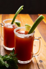 Mexican beer cocktail called michelada with celery on wooden background
