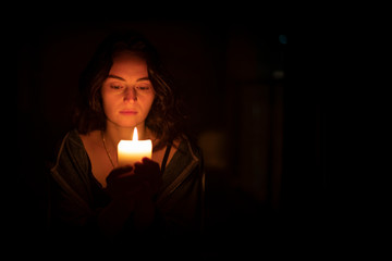 A sad religious orthodox brunette girl with brown eyes looks piercing and sad looking, holding a...