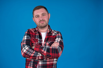 Front view of bearded man posing with folded arms isolated on blue background