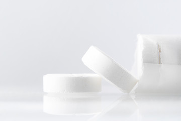 White large pills on a mirror surface with copy space. Medicines on a white background close up.