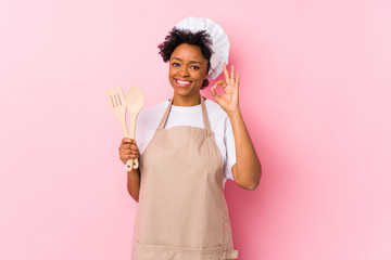 Young african american cook woman cheerful and confident showing ok gesture.