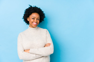 Middle aged african american woman against a blue background isolated smiling confident with crossed arms.