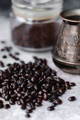 Aromatic roasted coffee beans, vintage metal turk and glass jar with milled coffee. Concept of coffeemania, morning ritual, delicious and stroung drink. Close up, macro, front view