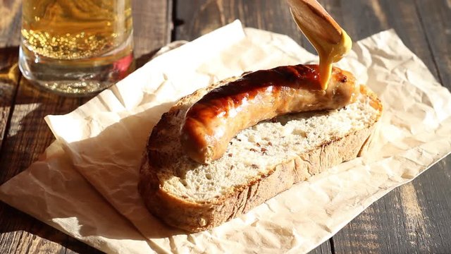 Bread with grilled sausage and mustard. German cuisine. Sandwich. Bbq. Rustic. Video.