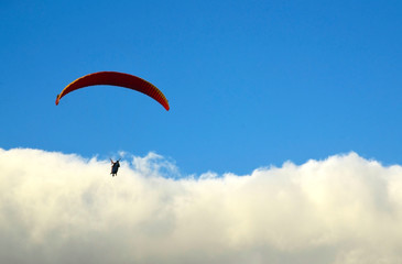 Paraglider flying against blue sky with clouds in south Tenerife,Canary Islands,Spain.Paragliding.Concept of extreme sport activity.Selective focus.