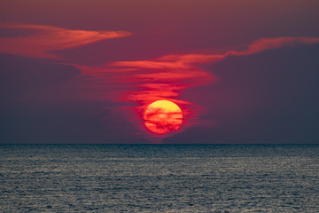 Obraz premium Красивый, красочный и контрастный закат над морем, океаном. Горячее солнце освещает просторный пейзаж, отбрасывая блики лучей на водную гладь. Яркий солнечный восход. Путешествие и туризм.