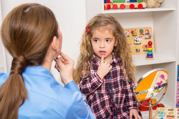 Young girl  in speech therapy office. Preschooler exercising correct pronunciation with speech...