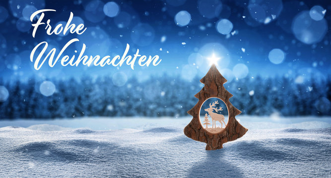 Weihnachtskarte frohe Weihnachten mit Weihnachtsbaum mit Stern im Schnee und Schneeflocken vor einem Wald in der Farbe blau