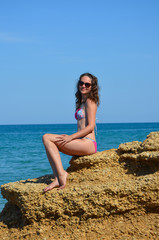 Young woman in a swimsuit and sunglasses on the seashore