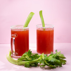 Mexican beer cocktail called michelada with celery on pink background