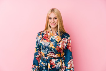Young blonde woman wearing a kimono pajama happy, smiling and cheerful.