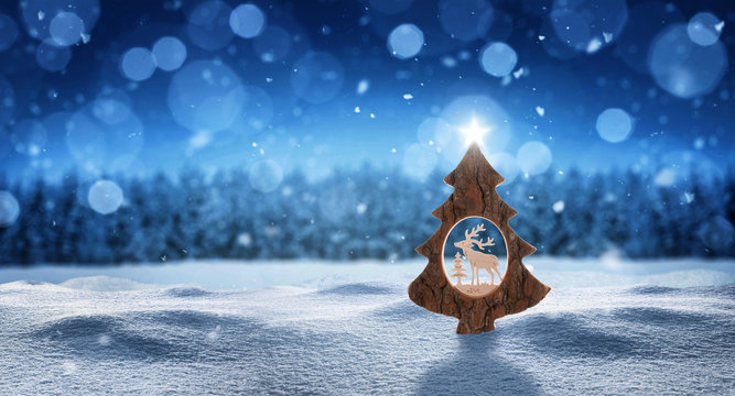 Weihnachtskarte mit Weihnachtsbaum mit Stern im Schnee und Schneeflocken vor einem Wald in der Farbe blau