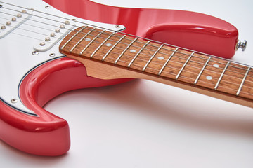 Fragment of a red electric guitar on a white background. Part of the guitar. Music object.