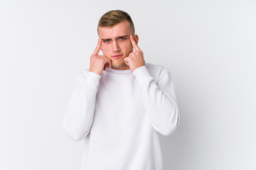 Young caucasian man on white background focused on a task, keeping forefingers pointing head.