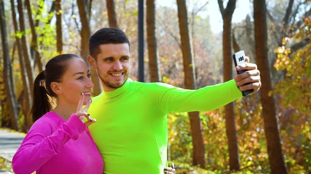 Athletic couple taking funny selfie after jogging in autumn park