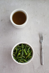 Cooked green beans in olive oil with garlic and lemon. A cup of green tea.