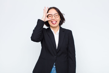young businesswoman smiling happily with funny face, joking and looking through peephole, spying on...