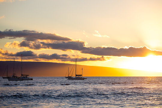 sail boats on the ocean at sunset
