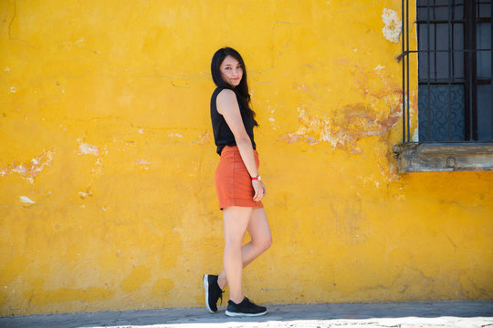 Traveling girl in colonial city - Hispanic woman standing in front of yellow old wall - Young woman is posing in the streets of the historical city Guatemala