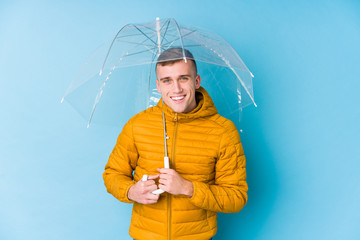 Young caucasian man holding an umbrella laughing and having fun.