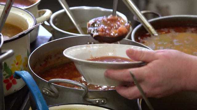 close-up. hand with a saucer. Pours borsch in a plate. soup in a plate.
