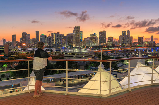 Woman on a cruise ship overlooking the Miami skyline after sunset