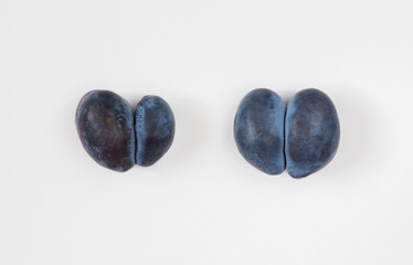Trendy ugly food concept. Two purple plums on a white background.