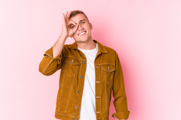 Young caucasian man isolated excited keeping ok gesture on eye.