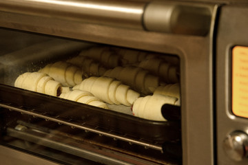 Baking tray with rows of fresh croissants in oven