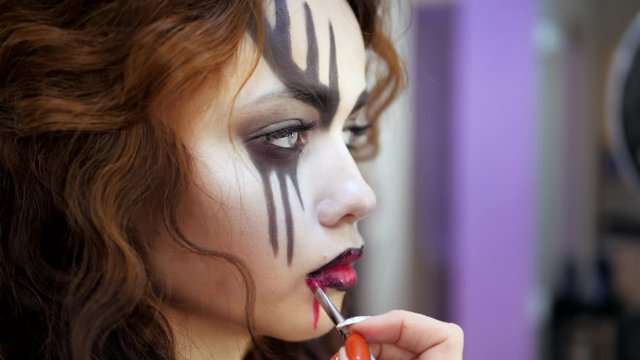 Easy Halloween Makeup. Applying makeup to the face. Drawing red blood on the face of a crying girl. A blood drinker.
