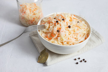 Homemade sauerkraut. Fermented food. Sauerkraut with carrots in a white bowl on a white background close up.