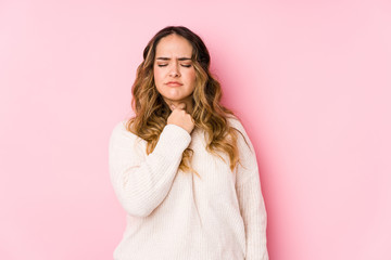 Young curvy woman posing in a pink background isolated suffers pain in throat due a virus or infection.