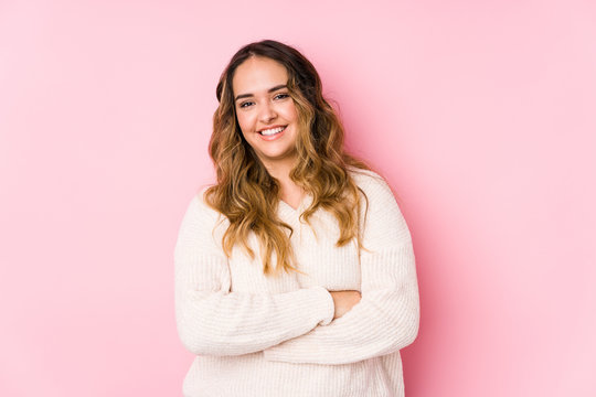 Young curvy woman posing in a pink background isolated laughing and having fun.