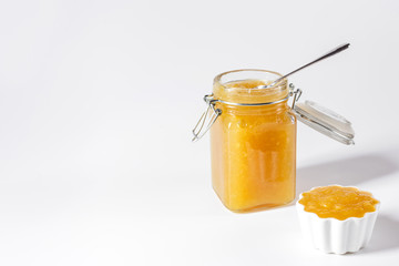 Homemade delicious fruit jam in glass jar and bowl on white background. Copy space.