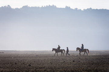 Silhouette of tourist ride a horse aside with his local tour guide. Mount Bromo is an active volcano and one of the most visited tourist attractions in East Java, Indonesia.