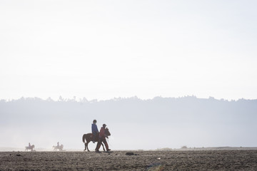Silhouette of tourist ride a horse aside with his local tour guide. Mount Bromo is an active volcano and one of the most visited tourist attractions in East Java, Indonesia.