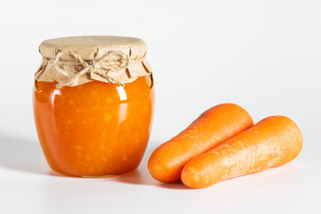 Juicy homemade carrot jam in glass jars on a white background.