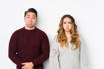 Young couple posing in a white background blows cheeks, has tired expression. Facial expression concept.