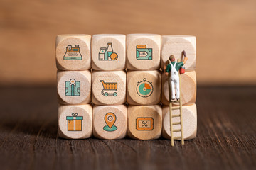 little painter figure and cubes with sales icons on wooden background