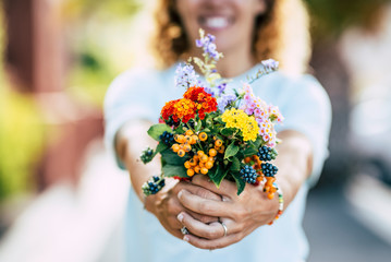 Spring flowers and free happiness concept - unrecognizable defocused caucasian people woman taking and showing a group of coloured fresh flowers in front of the camera - Powered by Adobe