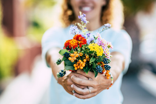 Spring flowers and free happiness concept - unrecognizable defocused caucasian people woman taking and showing a group of coloured fresh flowers in front of the camera
