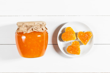 Homemade jam in a glass jar on a white wooden background.