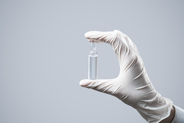 Ampouled solution in a hand wearing glove. Injection medicine in a glass capsule, concept of...