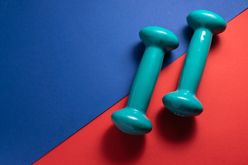Two dumbbells on creative blue and red background with copy space for your text. Sport and fitness concept. Healthy lifestyle concept.