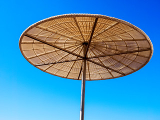 Straw sunshade in sunny summer day, tropical background.