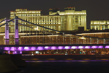Moscow cityscape at the winter sunset. Illuminated Krymsky Bridge over Moskva River and Ministry of Defence reflecting by purple and gold colors on the water surface. Telephoto lens