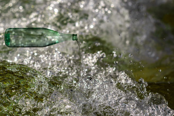 digital composite image of glass bottle that pours water into fresh frozen motion wave of riverbed