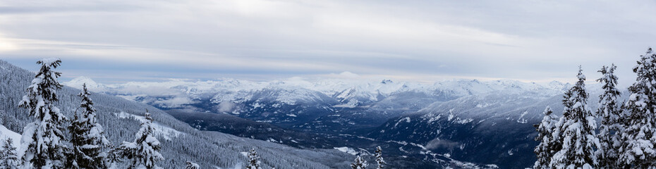 Fototapeta premium Whistler, British Columbia, Canada. Beautiful Panoramic View of the Canadian Snow Covered Mountain Landscape during a cloudy and foggy winter evening.
